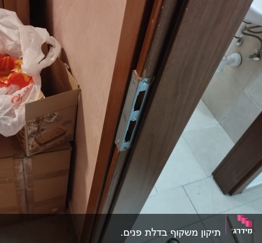 דלת עץ עם מנעול מותקן וכלי עבודה על הרצפה